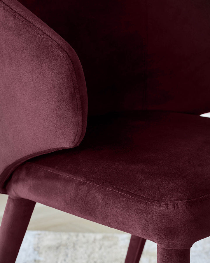 Ethan Dining Chair in plum velvet, showing curved backrest and seat detail from side angle.