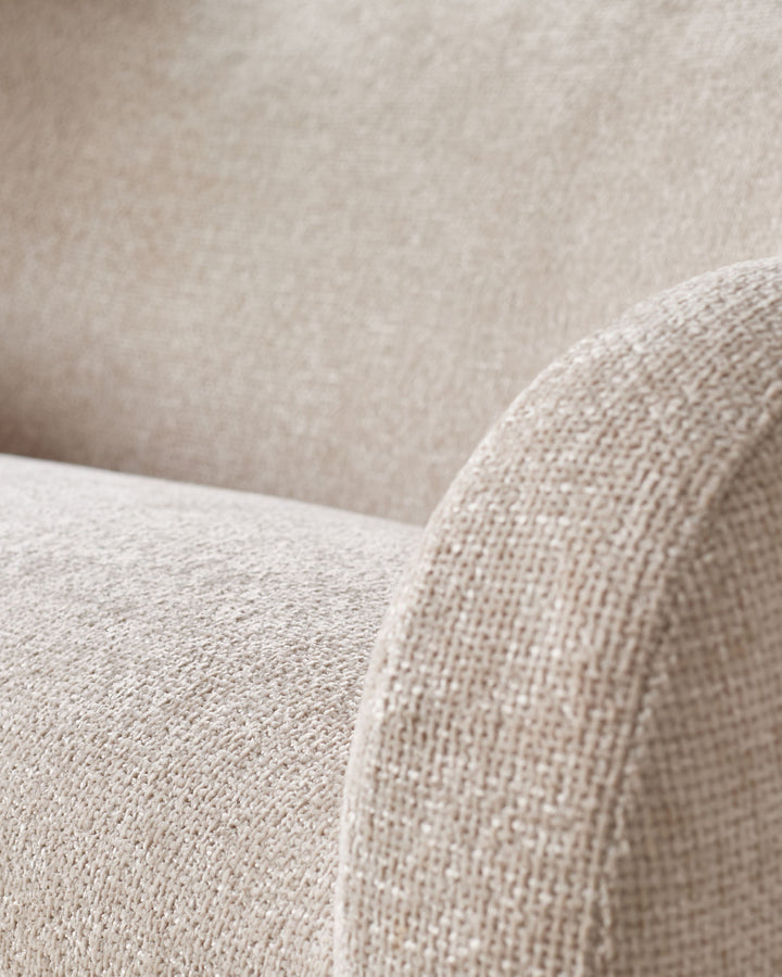 Close-up detail of natural beige fabric on Evelyn 3-seater sofa, showing textured weave and curved armrest.