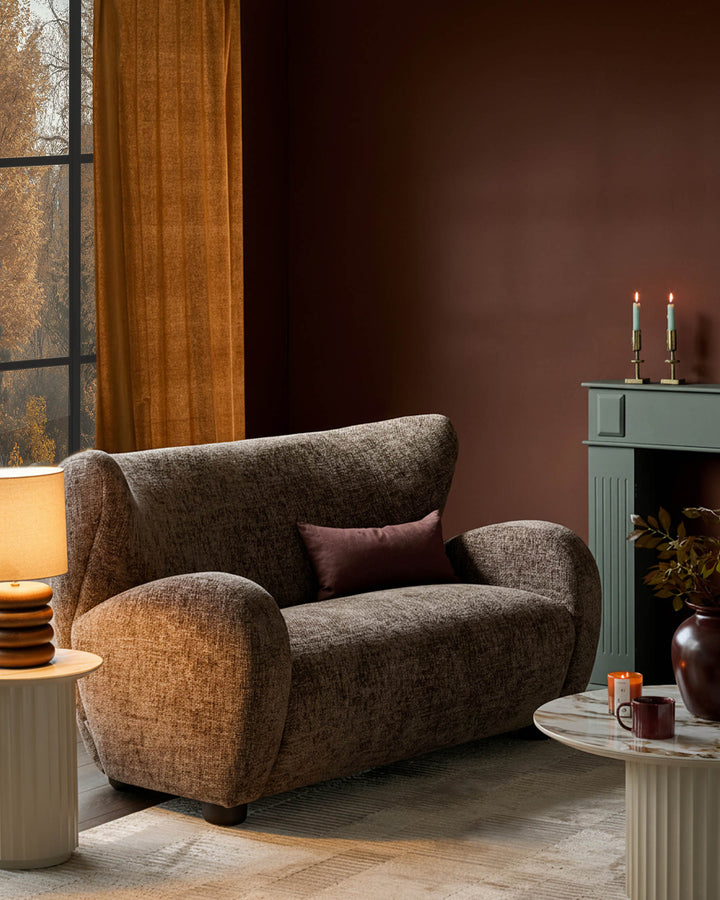 Evelyn 2-seater sofa in mocha fabric with curved arms and high back, styled in a warm living room setting.