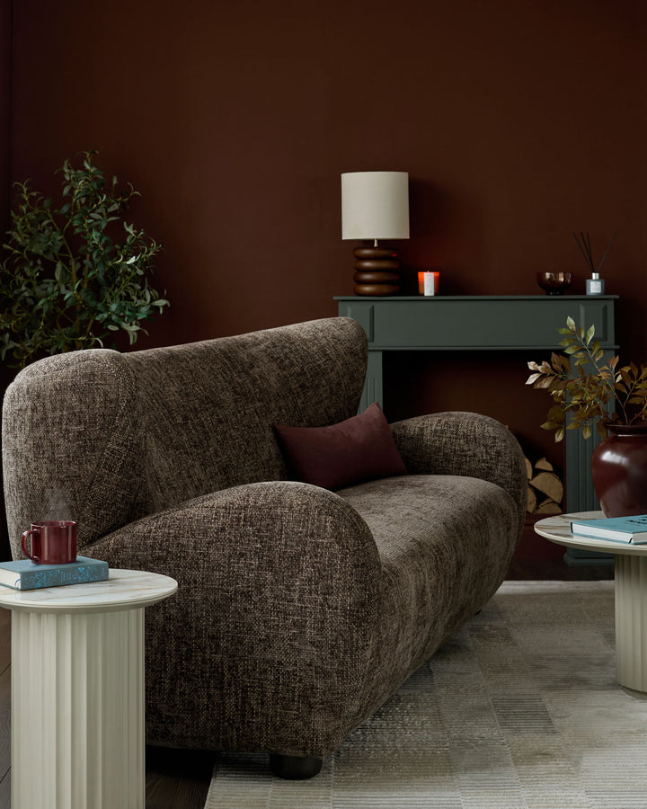 Evelyn 3-seater sofa in mocha fabric with curved, sculptural design and rounded armrests, styled in a burgundy living room.