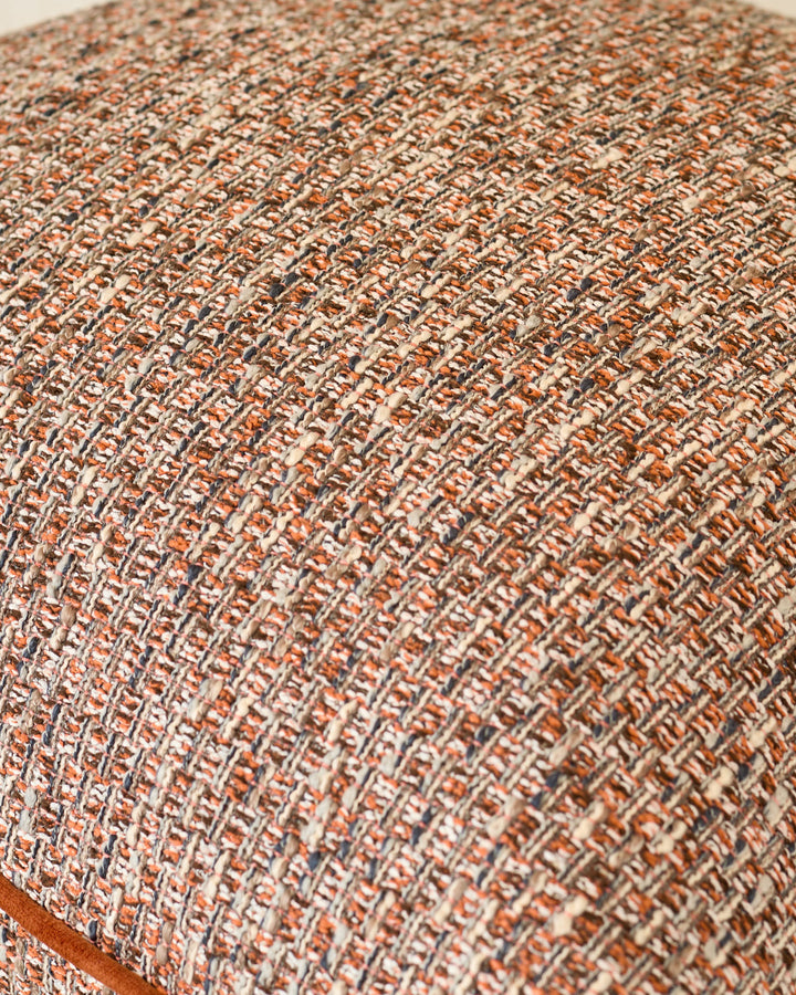 Close-up of Fabian large cushion in rust, showing textured woven fabric with warm orange and cream tones.