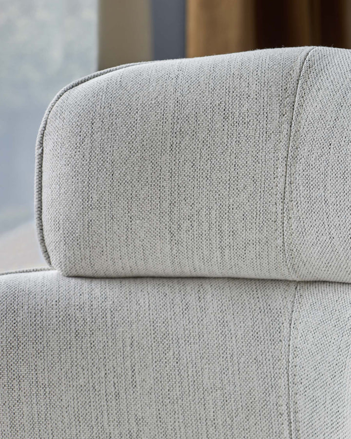 Close-up of a light grey, textured fabric sofa back and headrest. Modern, comfortable design.