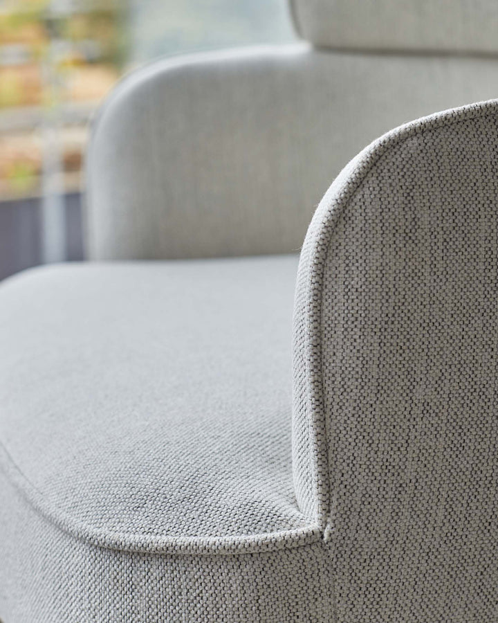 Close-up of a stylish, light grey, textured fabric armchair. Comfortable and modern seating for your home.
