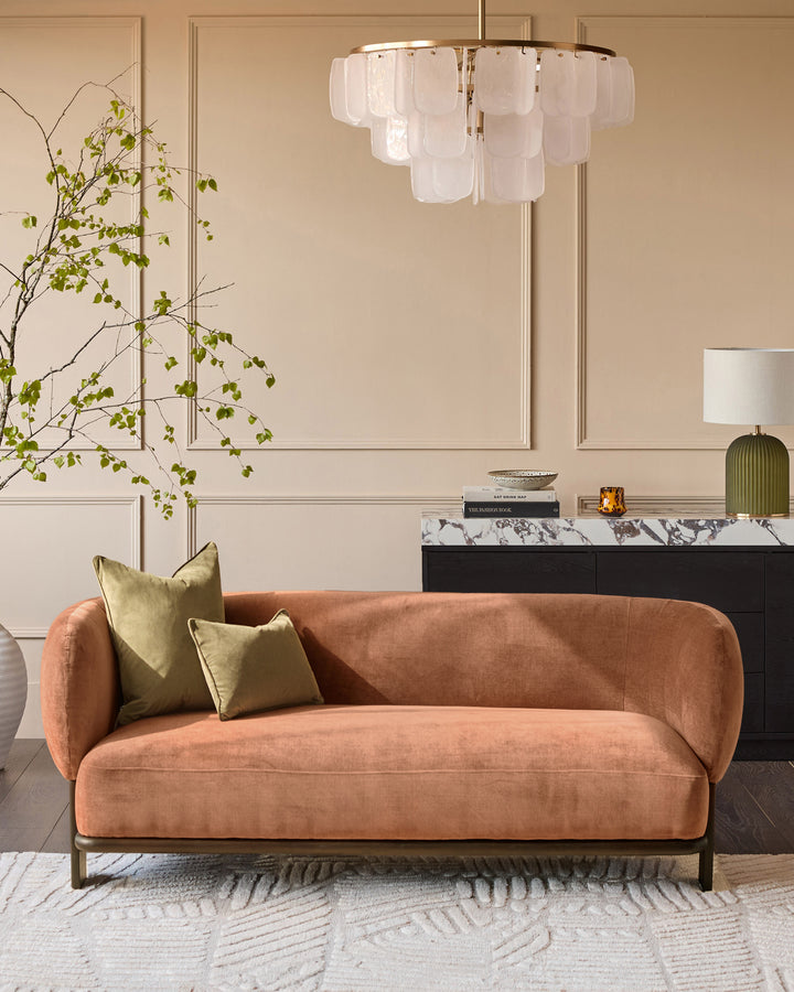 Florence 2-seater sofa in apricot fabric with dark wood base, displayed in a styled living room setting.