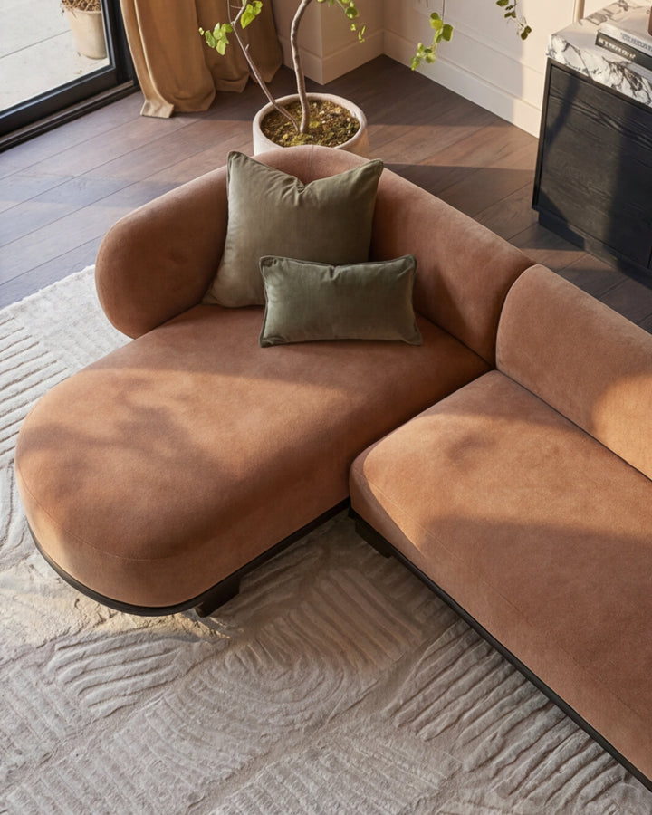 Florence left-hand-facing chaise sofa in apricot fabric with dark wood base, styled with sage green pillows in a modern living room.