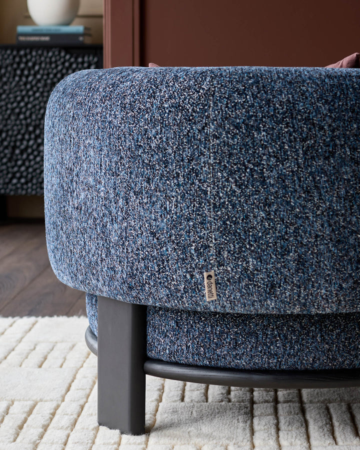 Florence armchair in navy weave fabric with dark wood legs, shown from side angle on cream rug.
