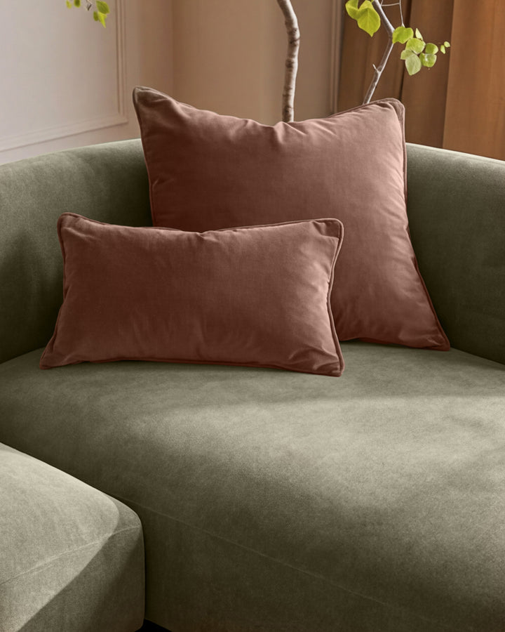 Florence right-hand chaise sofa in olive green with two burgundy velvet cushions and decorative branch with green leaves.