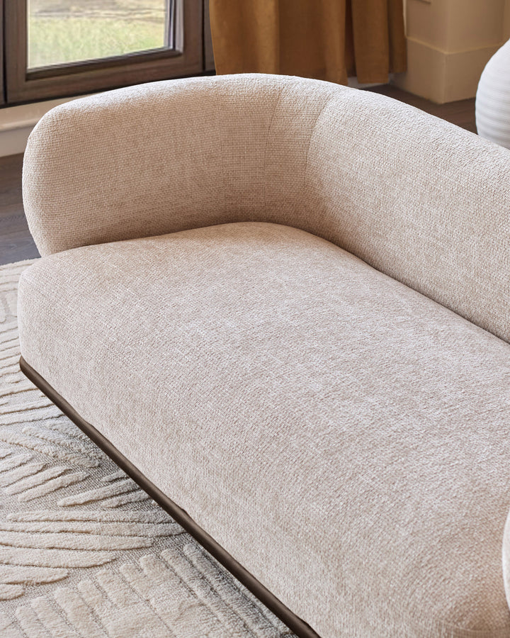 Florence 2-seater sofa in natural fabric with curved backrest and dark wood base, displayed at an angle in a bright room.