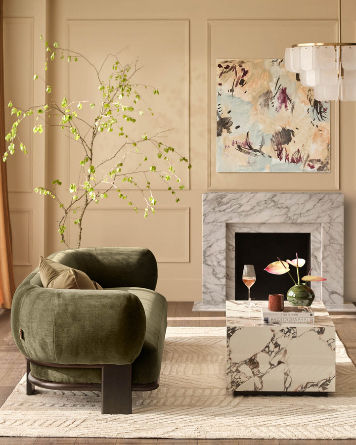 Olive green upholstered armchair with curved rounded shape and dark wood base, styled in a modern living room setting.