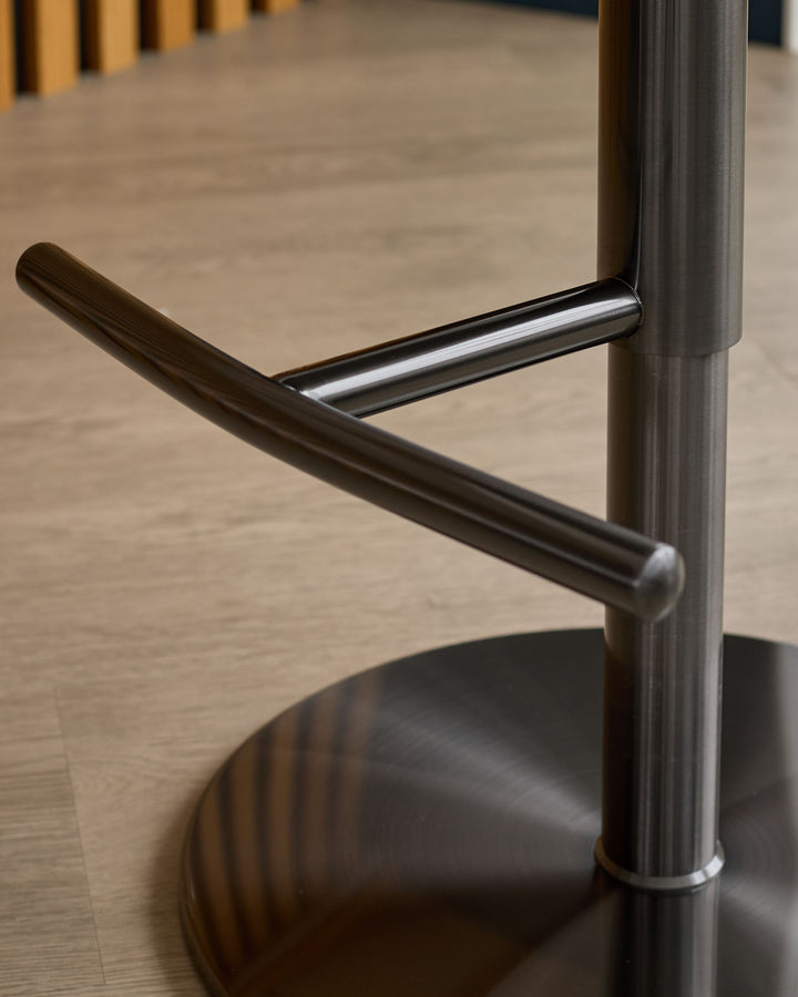 Myra gas lift bar stool showing chrome footrest and black curved armrest detail against neutral flooring.