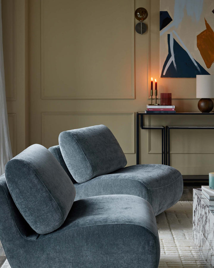 A stylish, grey, modular sofa sits in a cosy living room, complemented by modern art and a sleek side table.