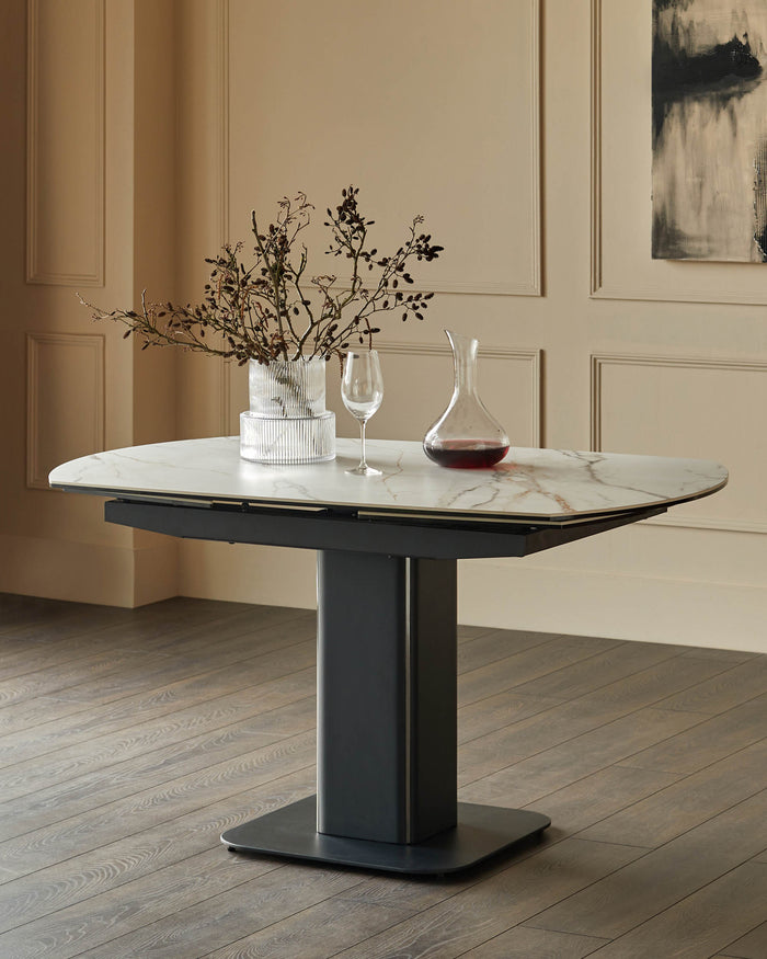 A contemporary dining table with a marble-effect top, a sleek dark grey base and stylish floral arrangement.