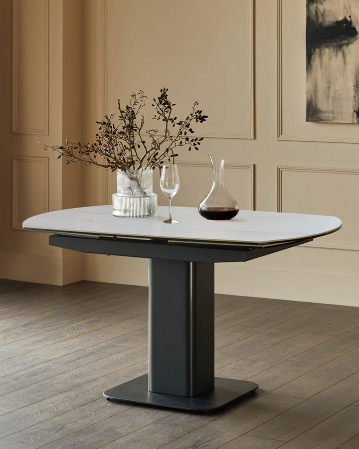 Fraser extending dining table with white ceramic top and charcoal base, styled with dried florals and wine decanter.