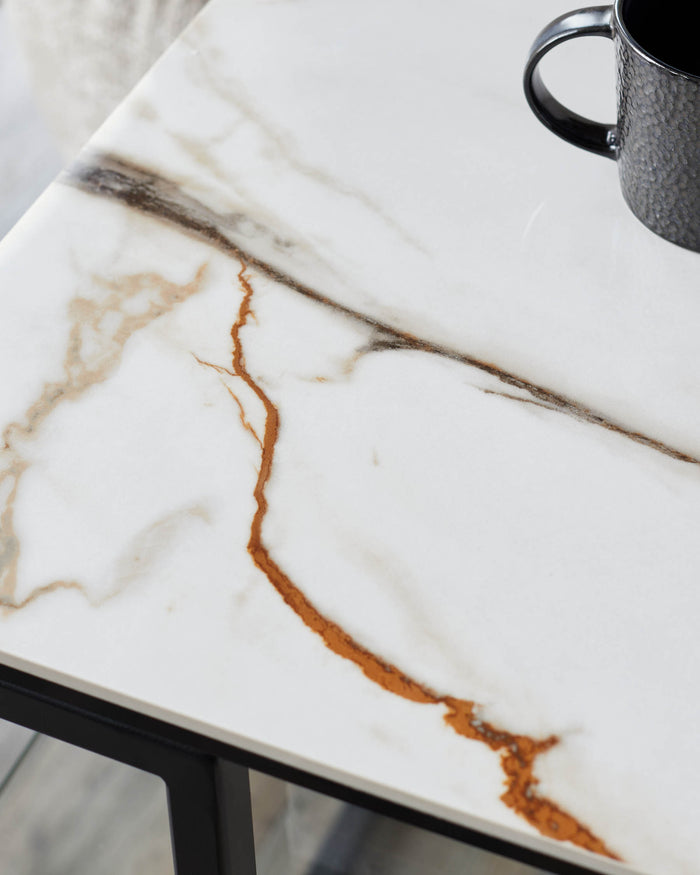 Close-up of a marble-effect side table with a black metal frame and textured mug. Modern and stylish furniture.