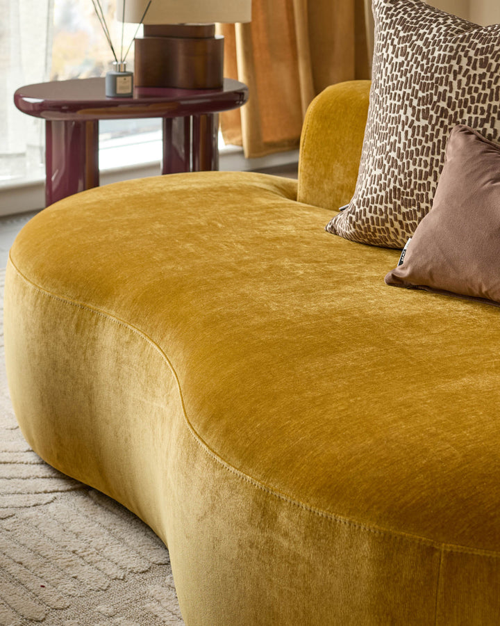 Gianna 2-seater sofa in ochre fabric, rounded sculptural form with curved seating surface, angled view.