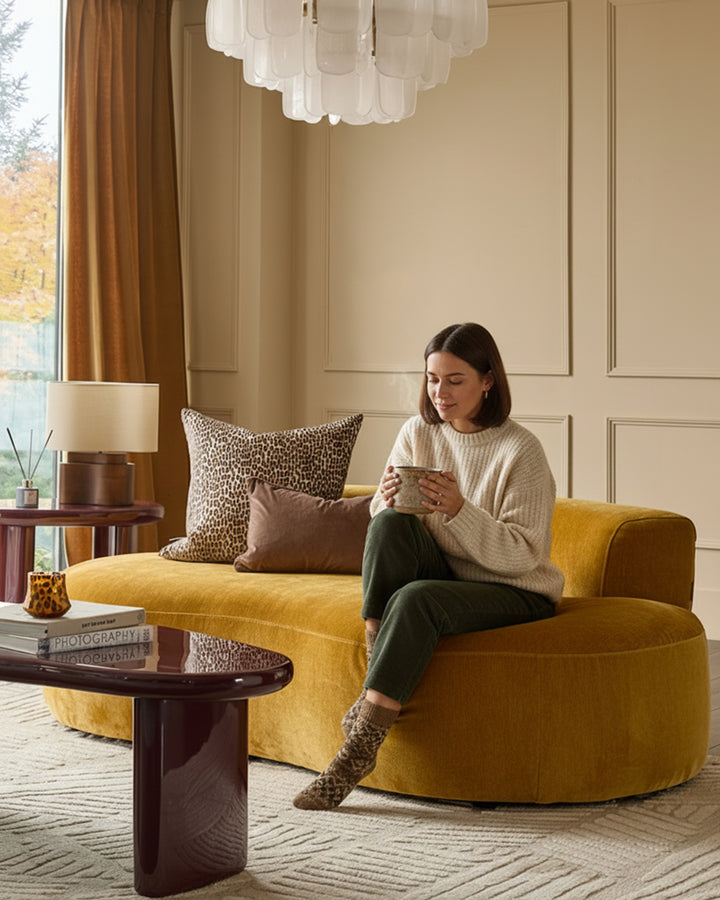 Gianna 2-seater sofa in ochre fabric, curved design, styled in a modern living room with decorative pillows and accessories.
