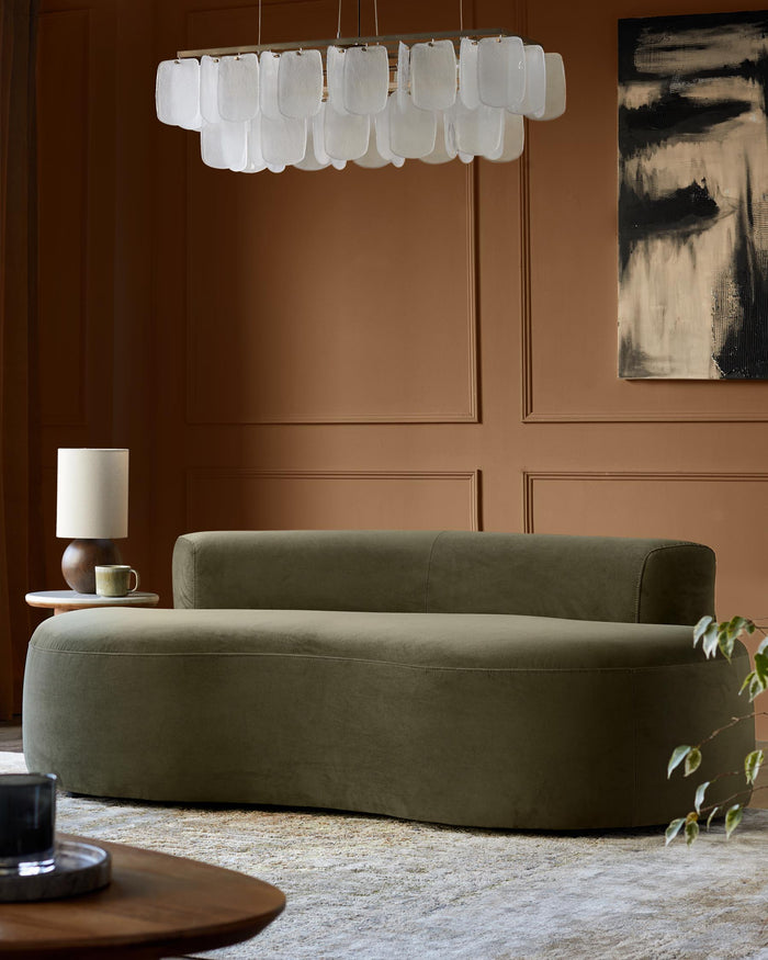 A stylish olive green sofa with matching ottoman, a lamp table, and a modern chandelier for a sophisticated living space.