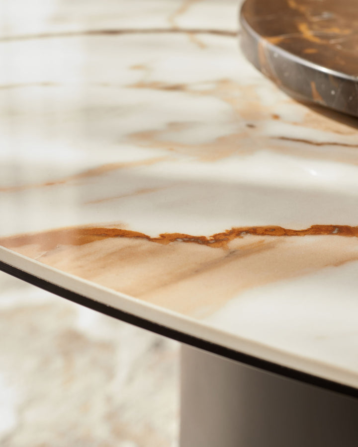 Close-up of a marble-effect table with a dark trim and a brown stand. Minimalist design for a modern home.