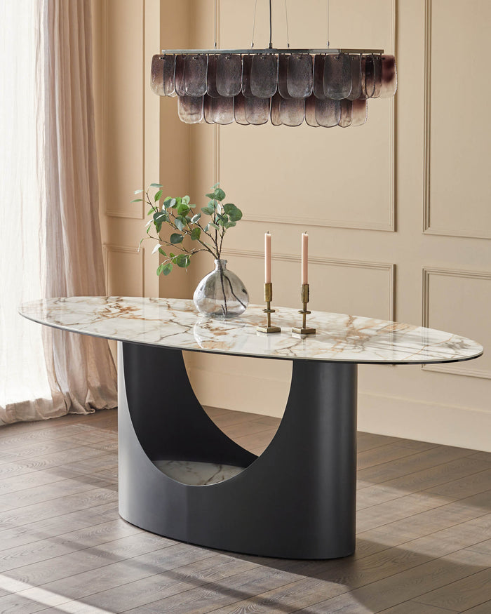 A modern dining space featuring a marble-topped table with a unique, curved pedestal base and a stylish chandelier.