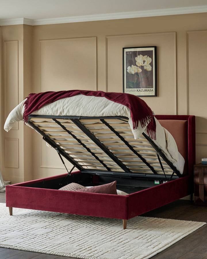 Rose velvet upholstered king-size ottoman bed with gas-lift storage mechanism fully open, displaying wooden slat base and interior storage space.