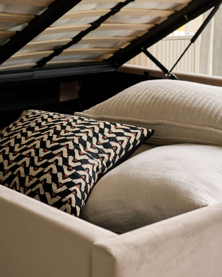 Grove King Ottoman Bed in champagne velvet with patterned cushion, overhead storage visible, angled bedroom view.