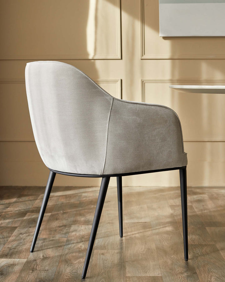 A stylish grey upholstered dining chair with black metal legs, sitting on a wooden floor.
