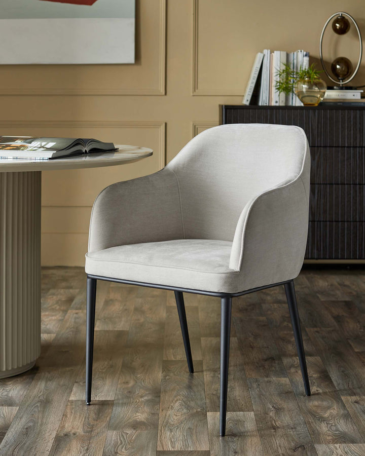 Upholstered dining chair with black metal legs next to a round table and wooden sideboard.