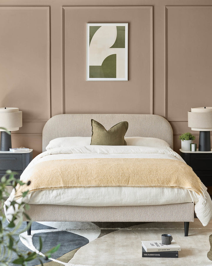 Bedroom featuring a neutral bed with side tables, lamps, and a framed print above the bed.