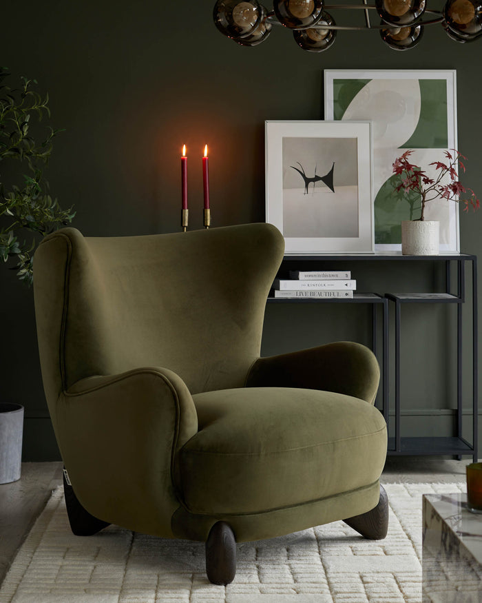 Olive green velvet armchair with dark wood legs, positioned on a geometric cream rug. Dark console table in background.