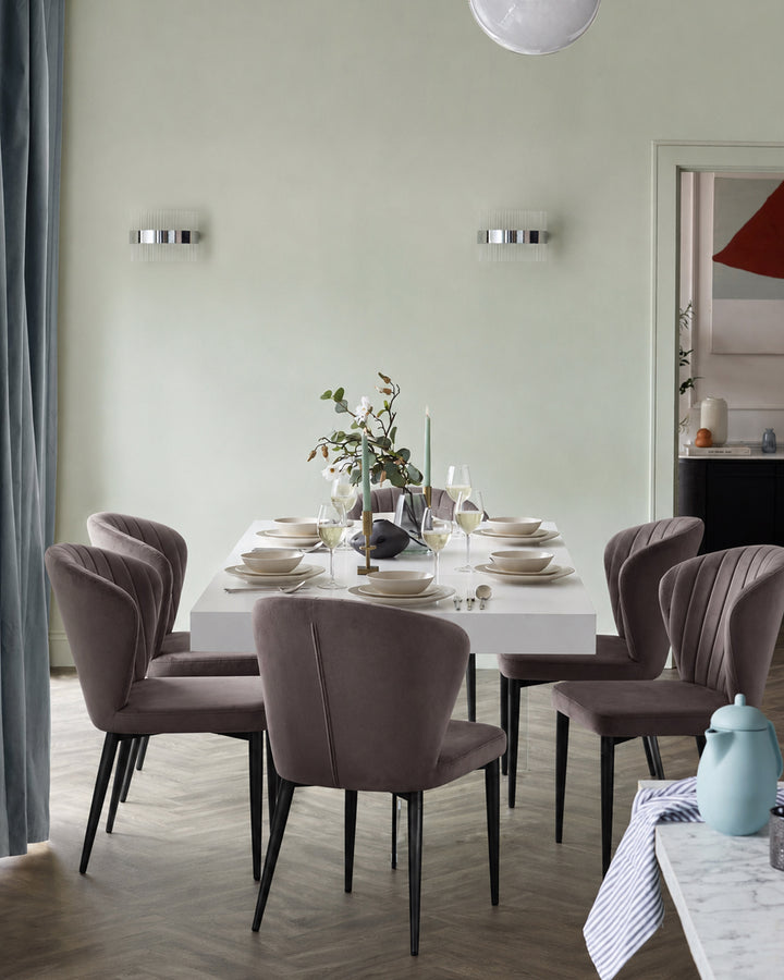 Harper dining chair in mocha velvet with black metal legs, shown in a dining room setting around a white table.
