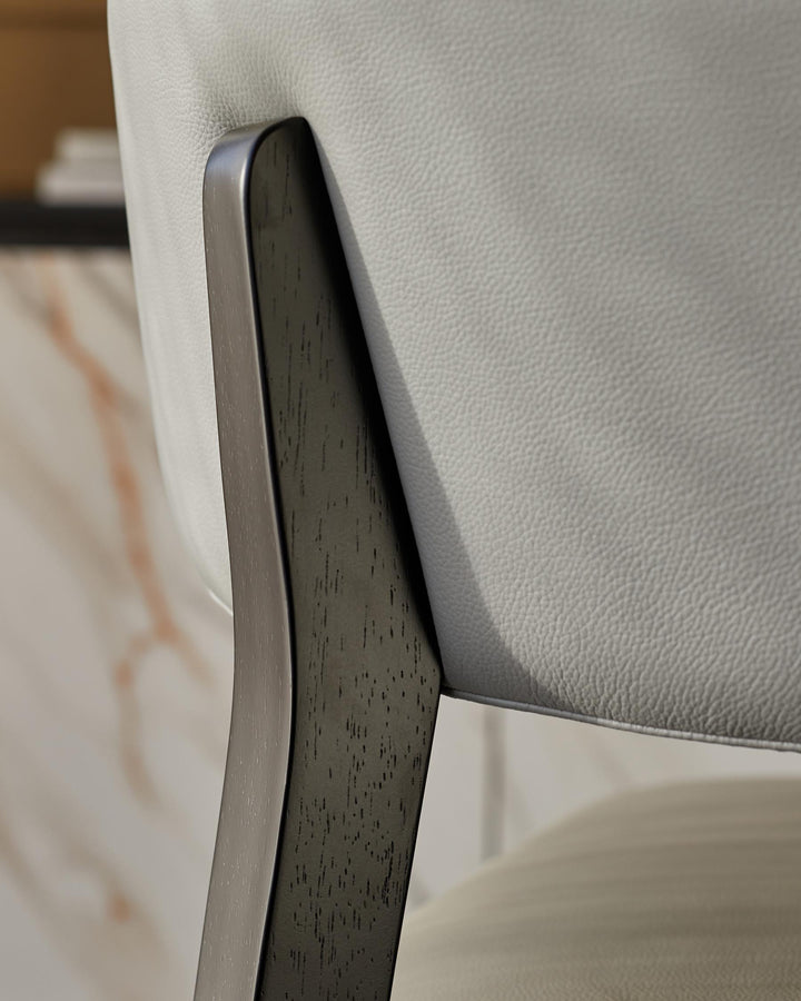 Close-up of a stylish, modern chair with light grey leather upholstery and a dark wood frame. Perfect for contemporary homes.