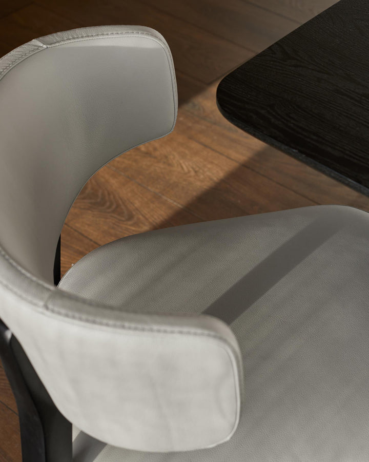 Modern grey chair with a sleek design, complemented by a dark wood table and warm wood flooring.