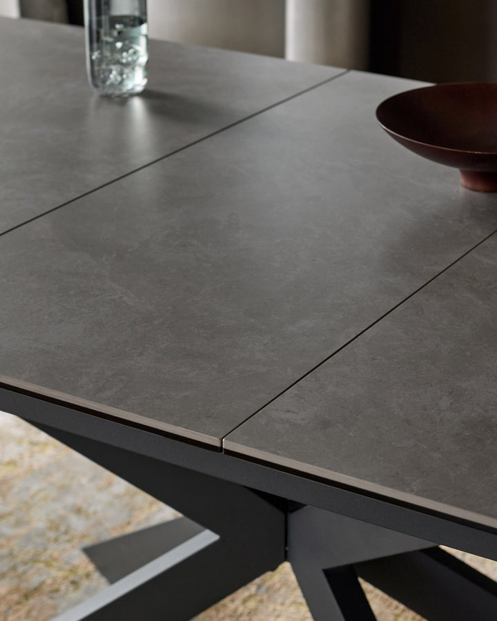 Hayden extending dining table in light grey ceramic with black base, showing extended leaf and polished surface detail.