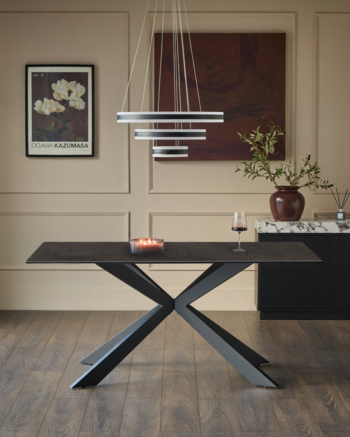 Hayden 6-seater dining table with dark grey ceramic top and black X-frame base in modern dining room setting.
