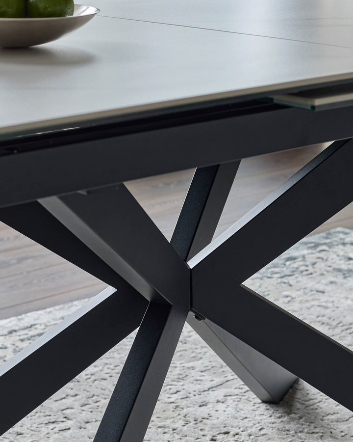 Hayden extending dining table with white ceramic top and black crossed-leg base, detail view of geometric leg design.
