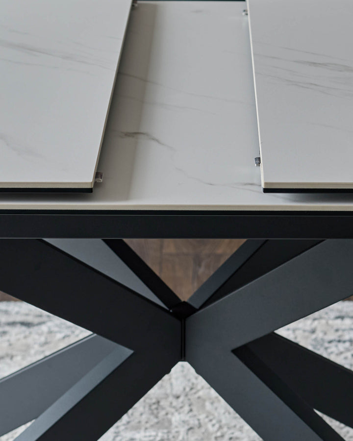 Hayden extending dining table with white ceramic top and black metal X-frame base, detail view.