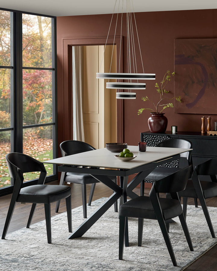 Hayden extending dining table in ceramic white with black X-frame base, shown in modern dining room setting.