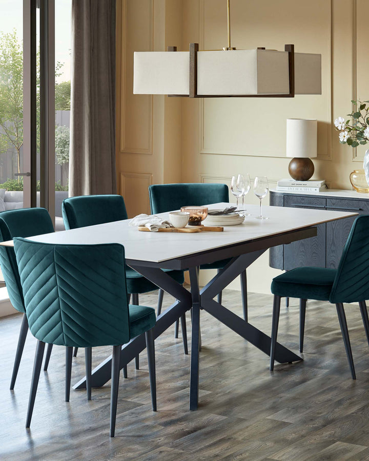 A dining set with a white table and dark green velvet chairs under a modern rectangular light fixture. Elegant dining room setting.