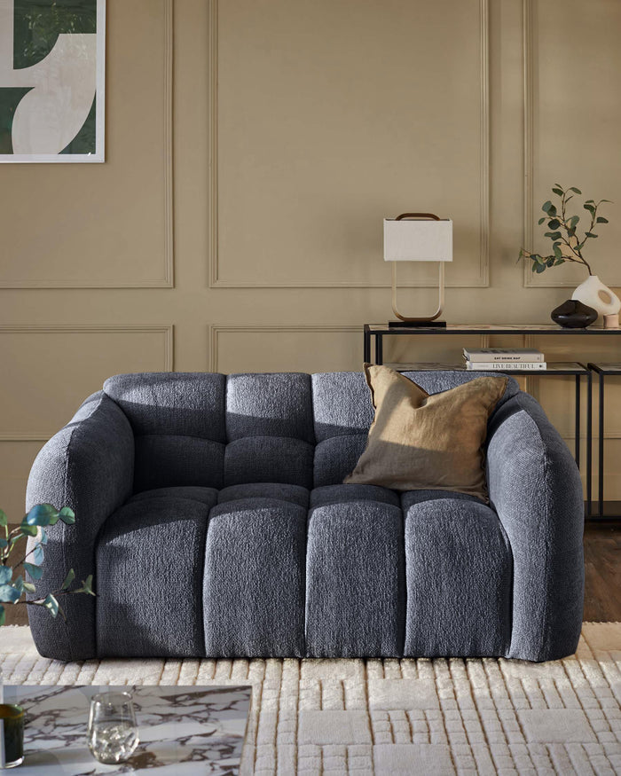 A stylish, contemporary blue sofa with a neutral cushion sits on a patterned rug in a warmly decorated room.
