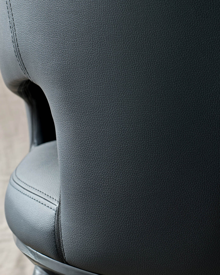 Close-up of a black leather office chair, showcasing the textured upholstery and stitching detail.