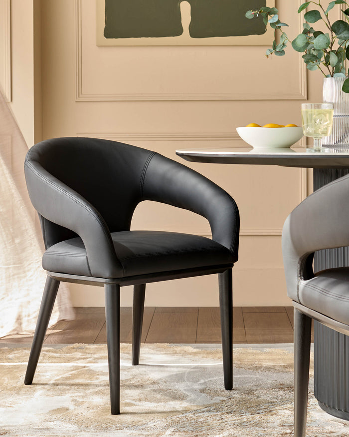 Stylish dark leather dining chairs with curved backs sit at a round table, creating a modern dining space.