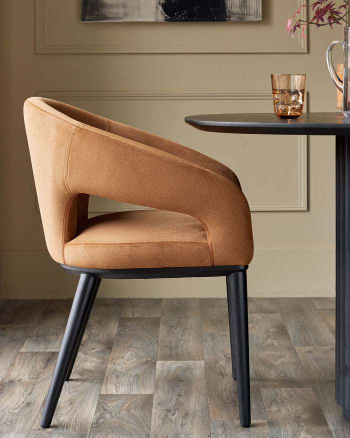 A stylish brown upholstered dining chair with a black frame, placed next to a round black table.