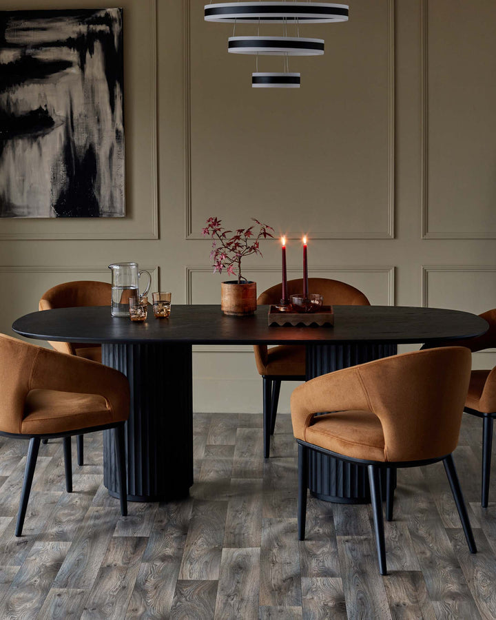 A dining set with a dark wood oval table, stylish chairs with tan fabric, and a modern light fixture.