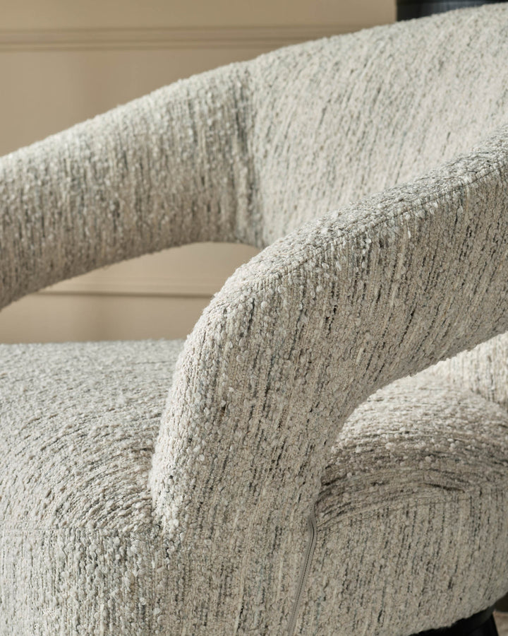 Close-up of a textured, light grey armchair with rounded armrests. Cosy and stylish seating.