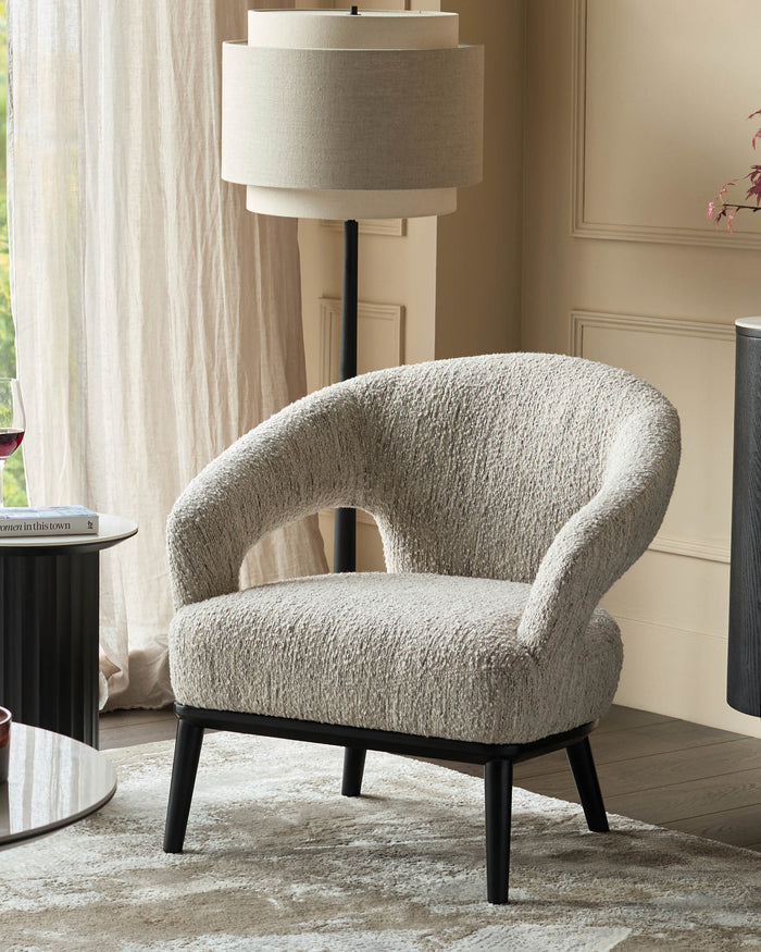 A stylish, modern armchair with black legs sits on a patterned rug in a bright living room setting.