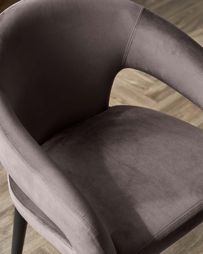 Elegant contemporary chair with plush, charcoal grey upholstery, featuring a curved backrest and seat with subtle stitching details, complemented by sleek black metal legs.