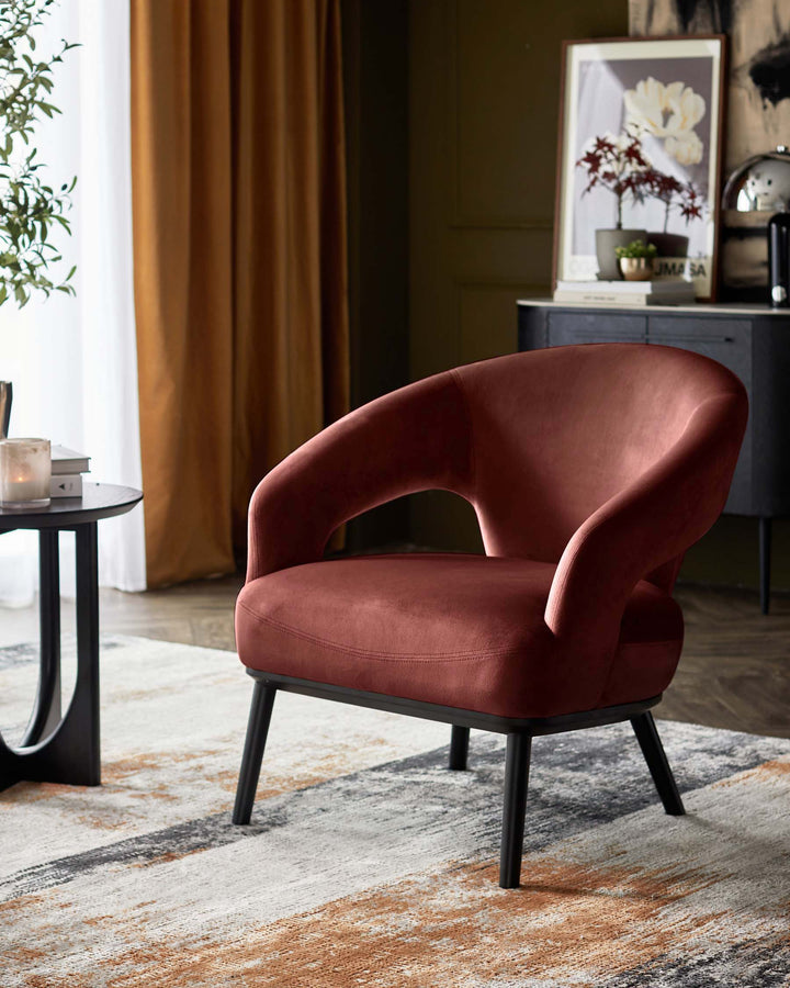 A plush red armchair with black legs sits on a patterned rug, beside a black side table. Stylish and modern.