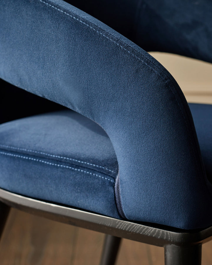 Close-up of a stylish, blue upholstered chair with sleek lines and a comfortable-looking seat.