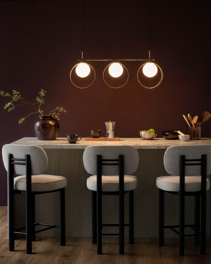 Chloe 3-pendant light with glass shades and silver chrome finish, suspended above a kitchen counter with bar seating.