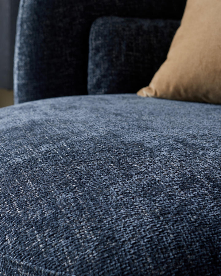 Close-up of a stylish, textured, navy blue sofa with a tan pillow. Modern and comfortable furniture.